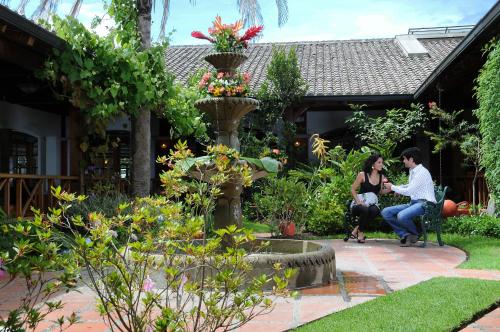 a man and a woman sitting in a garden at Hotel Rincon de Puembo; BW Signature Collection in Puembo