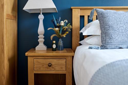 una cama con una lámpara y un jarrón de flores en una mesita de noche en The Barrington Boar, en Ilminster