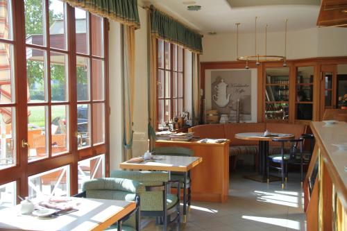 a restaurant with tables and chairs and windows at Simon - Hotel & Café in Bad Tatzmannsdorf