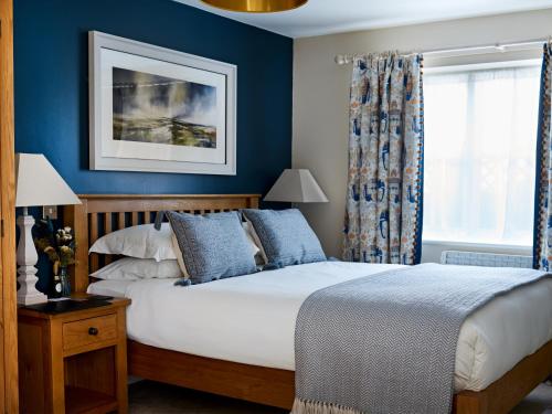 um quarto com uma cama com paredes azuis em The Barrington Boar em Ilminster