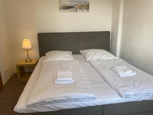 a bed with white sheets and towels on it at Pension Villa Ostseetraum in Warnemünde