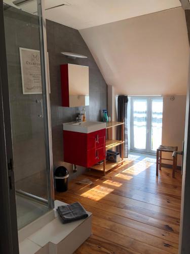 La salle de bains est pourvue d'un lavabo et d'une armoire rouge. dans l'établissement Gites de la Touche aux Pourvoirs, à Combourg