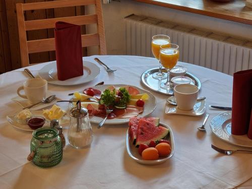 a table with plates of food and glasses of orange juice at Hotel Pension Geiger in Bad Tölz