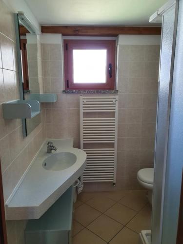 a bathroom with a sink and a toilet and a window at Bungalows in Camping Solarium in Domaso