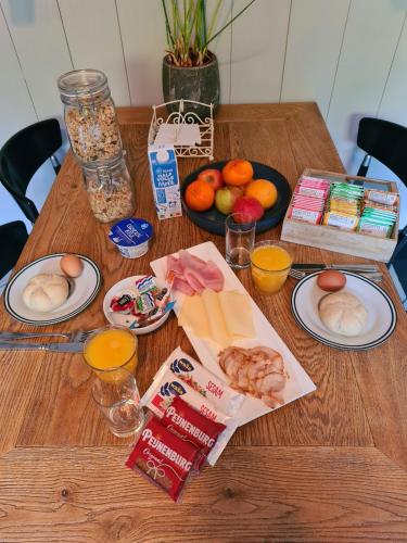 a wooden table topped with plates of food and fruit at Café Brasserie Het Heerenhuis in Het Kalf