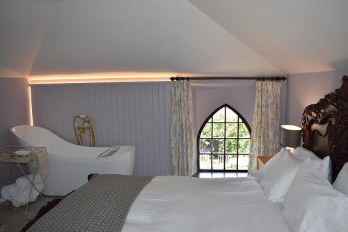 a bedroom with a bed and a bath tub and a window at Crug Glas Country House in St. Davids