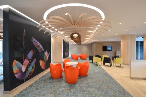a lobby with orange chairs and a clock on the wall at Danubius Hotel Bük in Bük