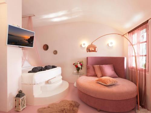 a living room with a round chair and a tv at Secret Gem Suites in Oia