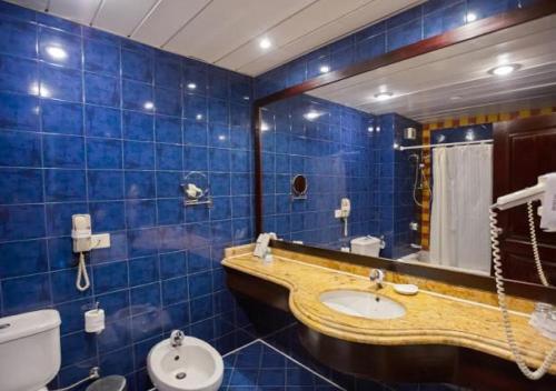 a blue tiled bathroom with a sink and a toilet at Porto Marina Resort & Spa Al Alamein in El Alamein