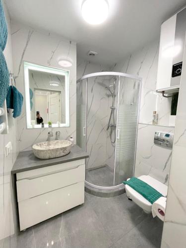a white bathroom with a sink and a shower at Luxury Emerald Apartments in Irpin'