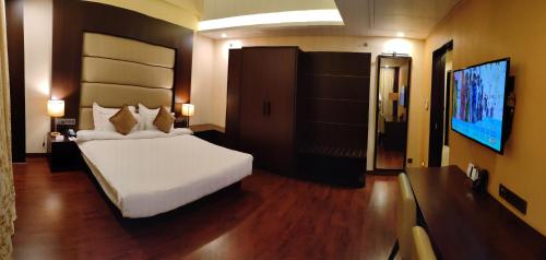 a bedroom with a large white bed and a flat screen tv at Vivanta Jamshedpur, Golmuri in Jamshedpur