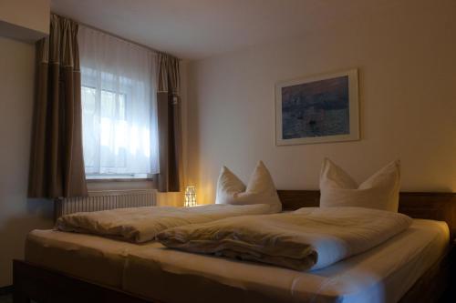 ein Schlafzimmer mit einem Bett mit weißen Kissen und einem Fenster in der Unterkunft Ferienwohnung Schwarzkollm in Hoyerswerda