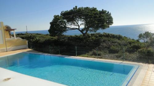 a blue swimming pool with a view of the ocean at Casa Sol - Vista Mar - Praia Benagil in Lagoa