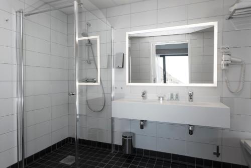 Baño blanco con lavabo y espejo en Thon Hotel Fosnavåg, en Fosnavåg