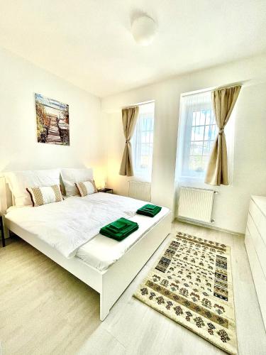 a bedroom with a large white bed and a rug at Libás Apartman in Keszthely