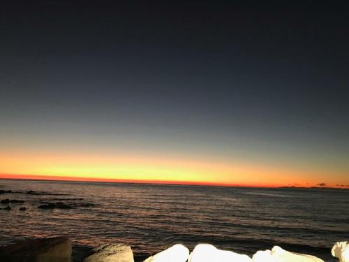 a sunset over the ocean with rocks in the foreground at Apartments Chiara mit Meerblick und Pool und Jacuzzi in Lovran