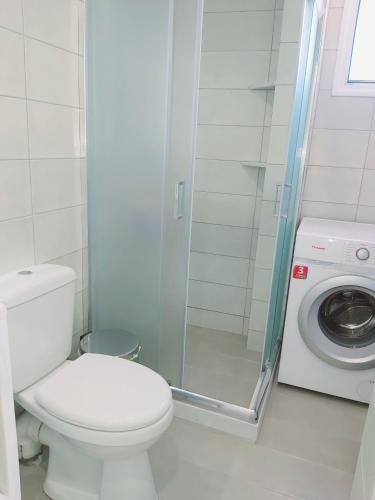 a bathroom with a toilet and a washing machine at Casa para ti in Porto Heli
