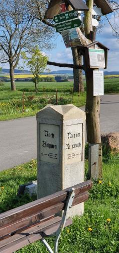 a trash can next to a bench next to a street at Zum Elleblick in Frauenstein