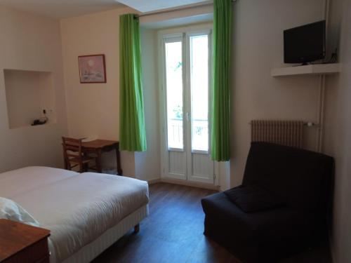 a bedroom with a bed and a chair and a window at Le Prieuré in Saint-Dalmas-de-Tende