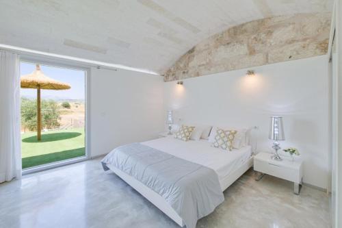 Dormitorio blanco con cama y ventana grande en Es Gassons, en Maria de la Salut