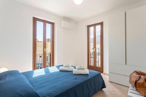 a bedroom with a blue bed and large windows at Poseidon Residence in San Vito lo Capo