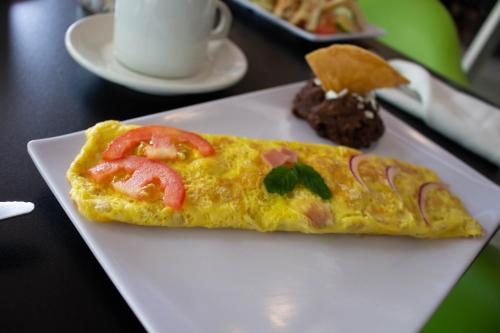 a white plate with an omelet with tomatoes on it at Hotel Diana del Bosque by DOT Urban in Morelia