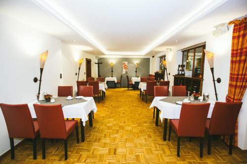 un restaurante con mesas blancas y sillas rojas en Schultes Landhaus en Delbrück