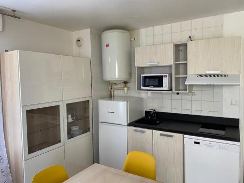 une cuisine avec des armoires blanches et des chaises jaunes dans l'établissement Résidence Fort de l'Eve - T2 à 380m plage M Hulot et commerces - St Marc sur Mer idéal famille proche La Baule P0rnichet avec parking privé, à Saint-Nazaire