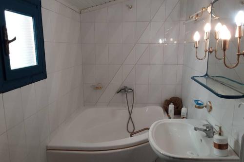 a white bathroom with a tub and a sink at john actors home in Kavala