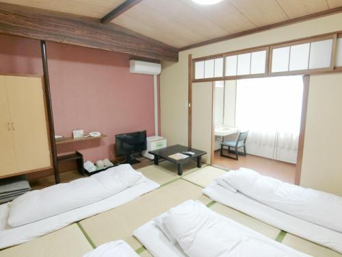 a room with three beds and a tv at Nogami Honkan in Beppu