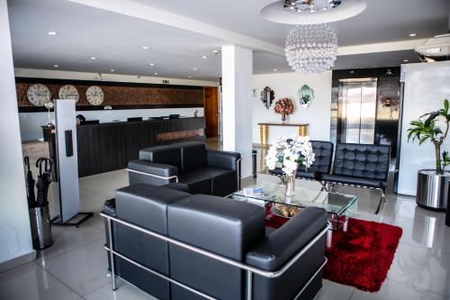 a salon with black leather furniture and a glass table at San Lucas Hotel in Sarandi