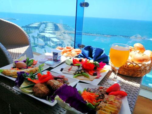 a table with two plates of food and a glass of beer at Jewel San Stefano Hotel in Alexandria