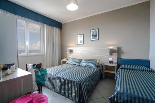 a hotel room with two beds and a window at HG Hotel Il Settebello in Marina di Cecina