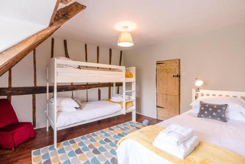a bedroom with two bunk beds and a staircase at Lavender Cottage in Saxmundham