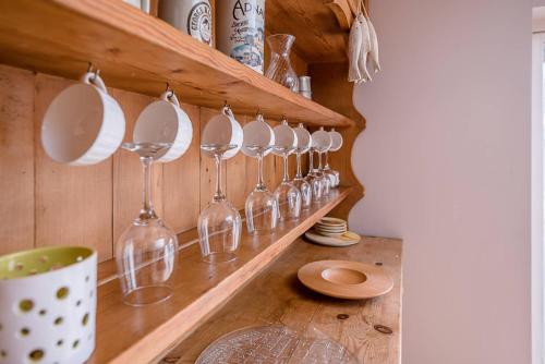 a row of wine glasses hanging on a shelf at Lavender Cottage in Saxmundham