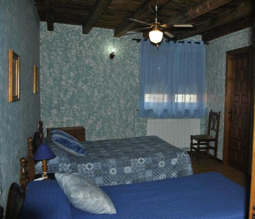 a bedroom with two beds and a ceiling fan at Hotel Rural Los Perales in San Vitero