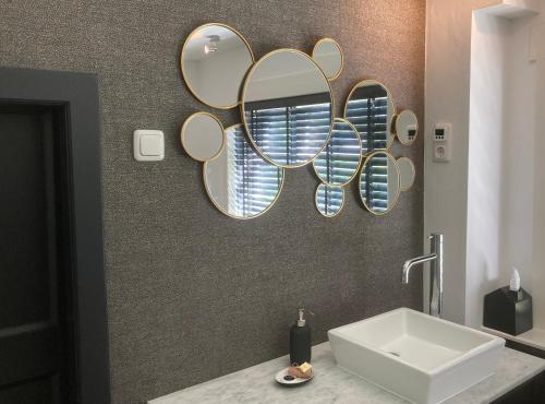 a bathroom with a sink and mirrors on the wall at Hoeve Altena Apartment in Woudrichem