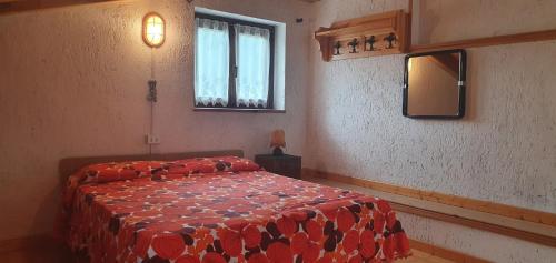 a bedroom with a bed with a red comforter and a window at Baita di montagna Stavel in Vermiglio