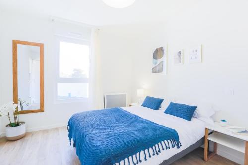 um quarto branco com um cobertor azul numa cama em Résidence senior mitoyenne aux Thermes em Châtel-Guyon