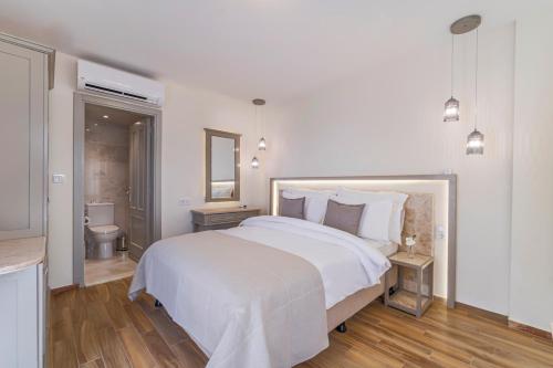 a white bedroom with a large bed and a bathroom at Elementa Boutique Hotel - Adults Only in Yalıkavak