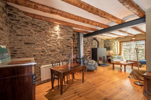 una sala de estar con una pared de piedra y una mesa. en Casa Mora Vall Fosca, en Central