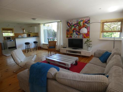 a living room with a couch and a table at Familiehuis Achter de Duijnhoeve Bakkum in Zuidbakkum