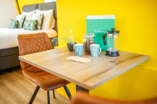 einem Holztisch mit Tassen und einem Mixer an einer gelben Wand in der Unterkunft Deluxe 35m2 City Center Suite - with Views in ’s-Hertogenbosch