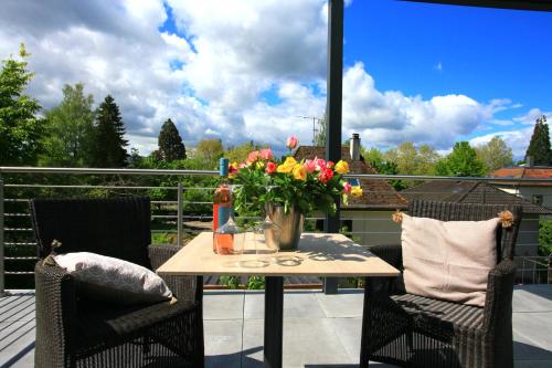 Una mesa con un jarrón de flores en un balcón. en Überlinger See-Apartments Apartment 10 Über-See, en Überlingen