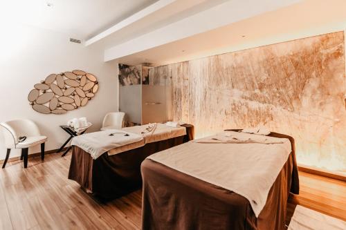 a treatment room with two beds and a wall at Alentejo Marmòris Hotel & Spa in Vila Viçosa