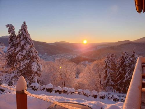 a winter sunset with snow covered trees and a fence at The View Fellering in Fellering