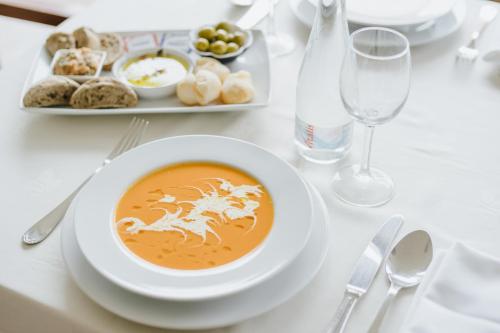 a table with a bowl of soup and a plate of food at Hotel Premium Porto Maia in Maia