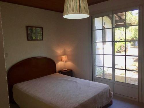 une chambre avec un lit et une grande fenêtre dans l'établissement Cottage with a big idyllic garden at the lake, à Lacanau