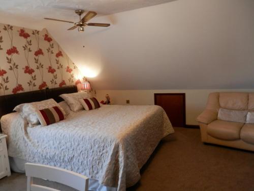 a bedroom with a bed and a chair and a ceiling fan at Finjaro in Sproughton