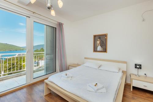 a bedroom with a bed and a large window at VILLA ALEXANDRA in Kumbor